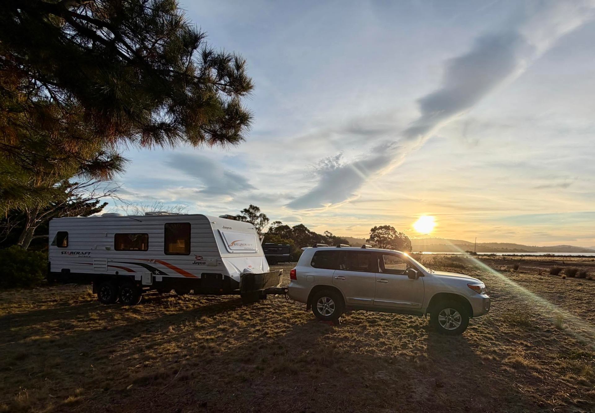 Caravan and tow vehicle parked at sunset by the water in Tasmania